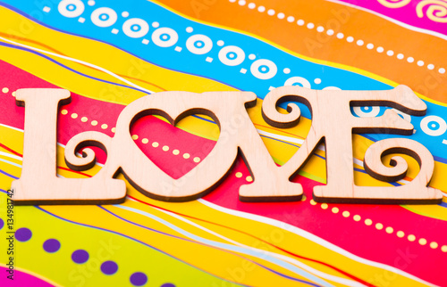 Wooden plaque "love" on a colorful background