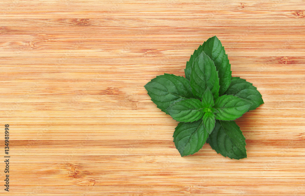 A bunch of fresh green mint on a wooden bamboo background A bunch of fresh green mint on a wooden bamboo background