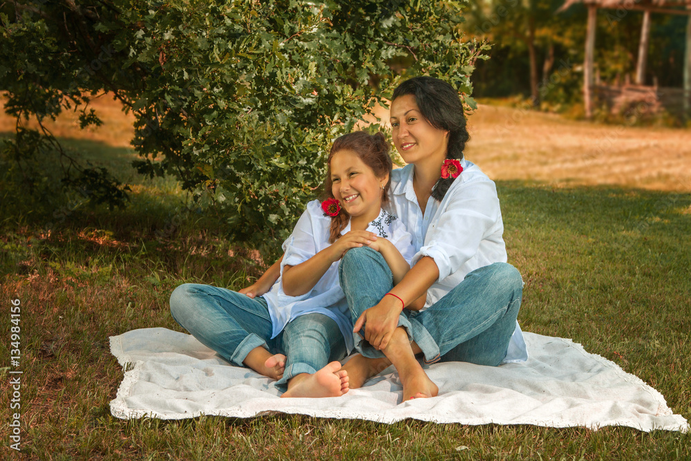 mother and daughter sitting under an oak tree mother and daughter sitting under an oak tree