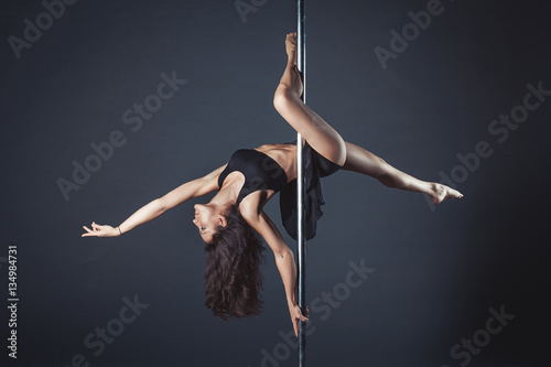 Young slim pole dance girl of asian appearаnce on a black studio background photo