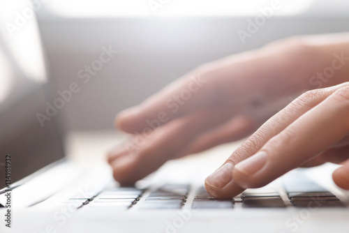 Hands typing on laptop keyboard close up