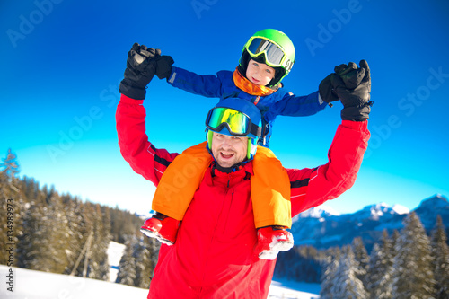 Little boy having fun with his father on the ski slopes in Alps