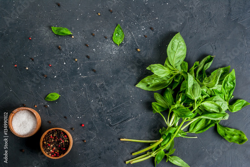 Cooking background. Kitchen table with spices (salt and pepper) and fresh basil, top view, copy space