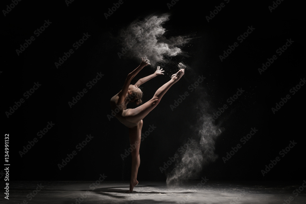 Graceful girl dancing in cloud of dust studio shot
