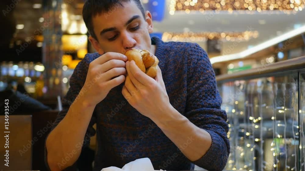 young handsome man eating hot dog