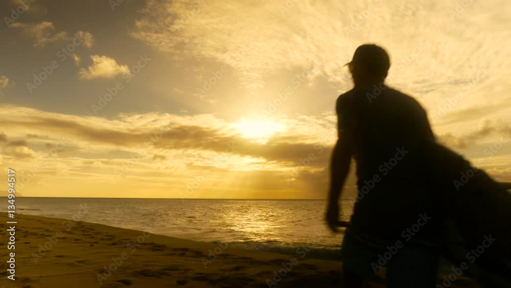 Young surfer on the beach waiting for perfect waves at sunset
