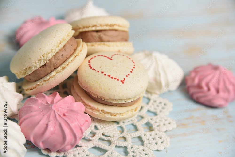 Macaroons and meringues on blue wooden background. french sweets.   