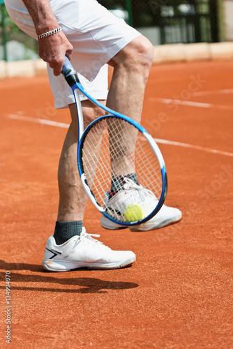 Tennis player. Taking ball with racquet from tennis court