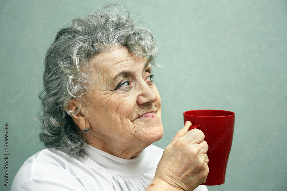 Grandmother with red cup on a grey Grandmother with red cup on a grey