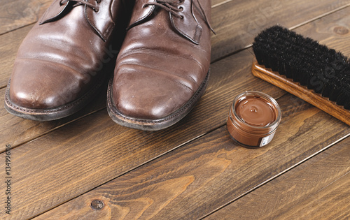 Old dirty shoes next to cleaning products on brown wooden table with. Copy space. Vertical shoot.