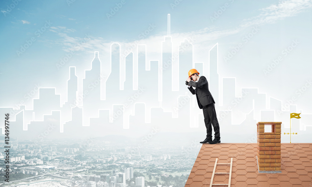 Engineer man standing on roof and looking in binoculars. Mixed media Engineer man standing on roof and looking in binoculars. Mixed media