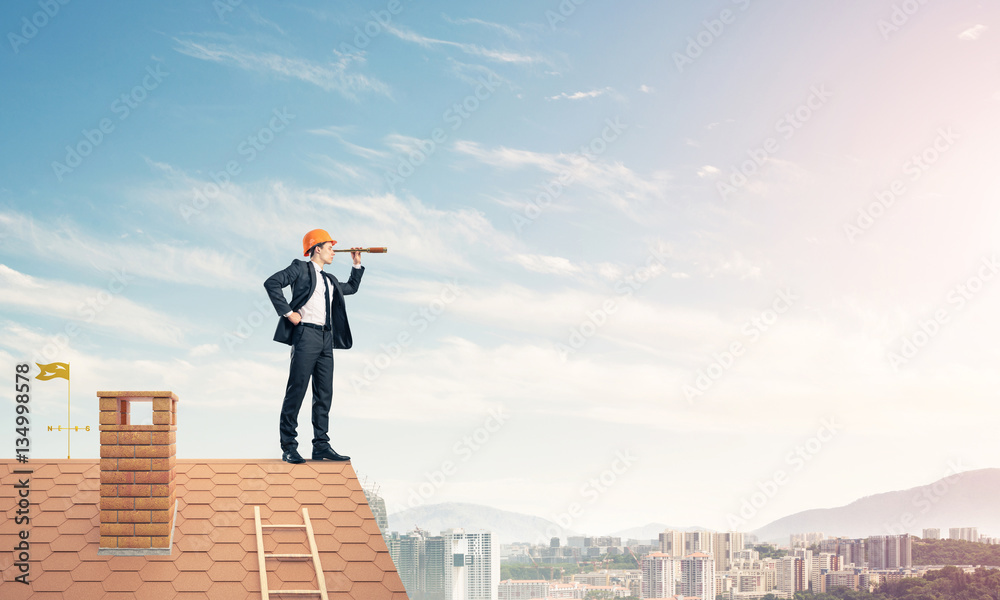 Engineer man standing on roof and looking in spyglass. Mixed med Engineer man standing on roof and looking in spyglass. Mixed med