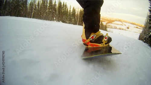 Snowboard board close-up. Legs snowboarder. Speed.