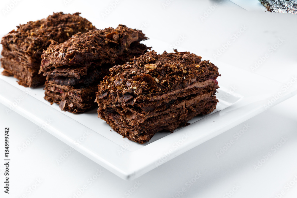 French Chocolate Napoleon cake of puff pastry with sour cream on a white plate close-up. Nutritious dessert. Selected Focus French Chocolate Napoleon cake of puff pastry with sour cream on a white plate close-up. Nutritious dessert. Selected Focus