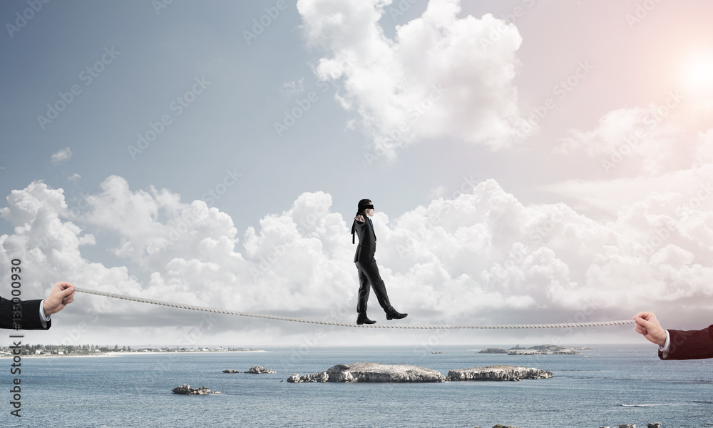 Business concept of risk support and assistance with man balancing on rope Business concept of risk support and assistance with man balancing on rope