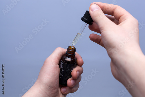 Man filling a pipette with beard oil