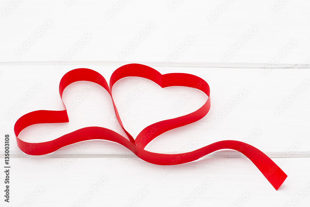 two hearts from red ribbon on white wooden background two hearts from red ribbon on white wooden background
