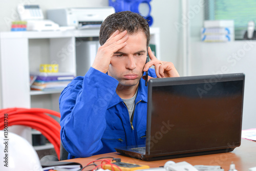 Frustrated man on telephone, looking at computer