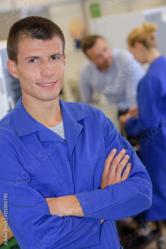 portrait of apprentice engineer posing crossing arms in laboratory
