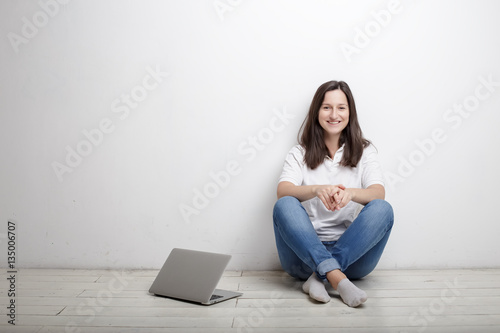 beautiful woman finished work contentedly sitting against the wall on the floor is opened notebook
