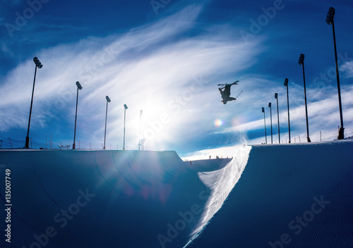Skier doing an inverted trick in winter snow halfpipe
