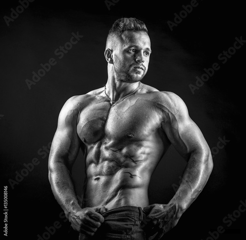 Young male fitness model poses on isolated background showing his perfect abs