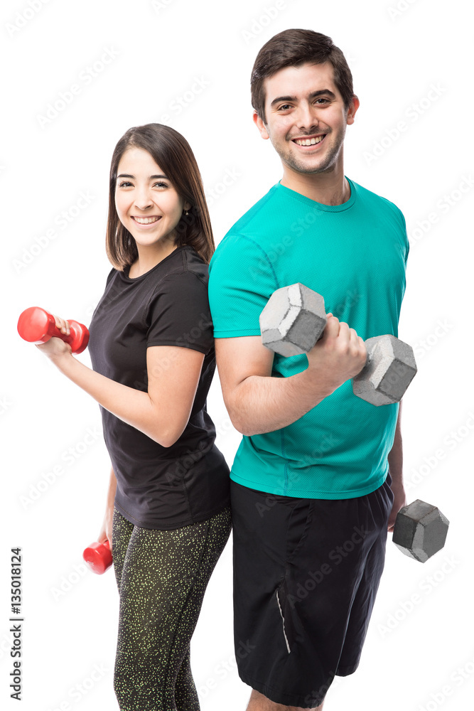 Cute couple lifting dumbbells and smiling Cute couple lifting dumbbells and smiling