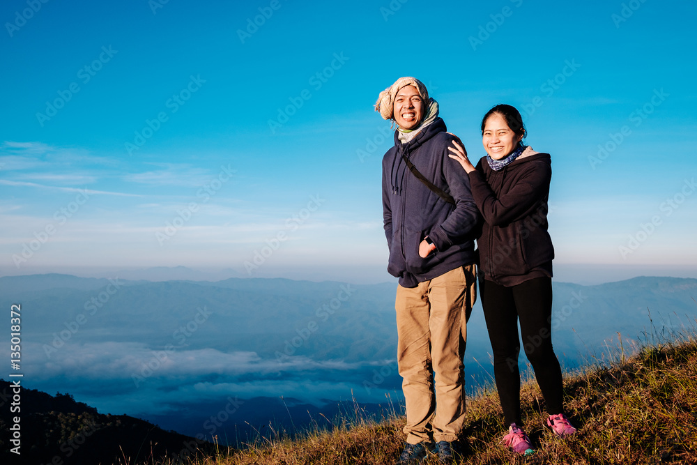 young adult asian couple standing together enjoys rise to the top of the mountain with light of morning in vintage style young adult asian couple standing together enjoys rise to the top of the mountain with light of morning in vintage style