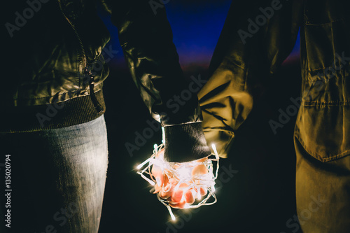 couple holding hands together with decorate light