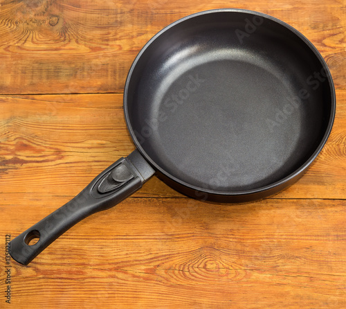 Frying pan with ceramic non-stick coating on wooden surface