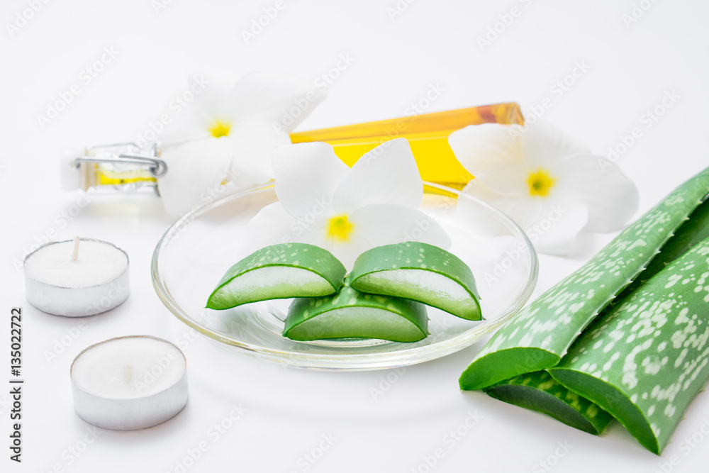 Fresh aloe vera slices with leaf, flowers, candels and oil on wh