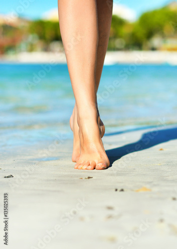 Close-up view of women's legs on the beach. © M-Production
