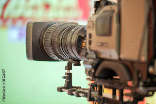 The camera with a long lens. Recording TV program. On green background.