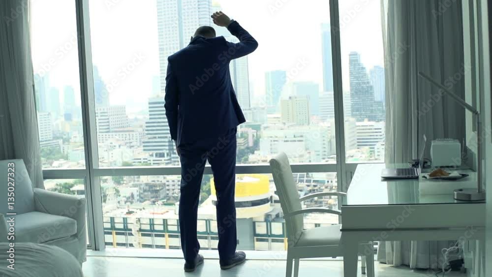 Sad, desperate businessman standing by window at home
Sad, desperate businessman standing by window at home