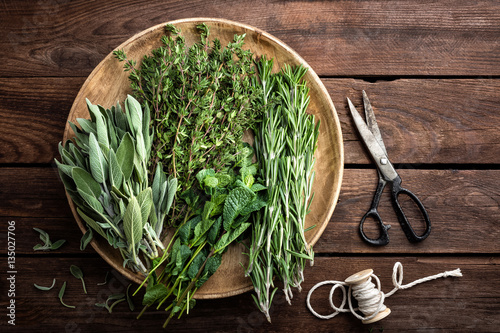 Obraz na plátně various fresh herbs, rosemary, thyme, mint and sage on wooden background