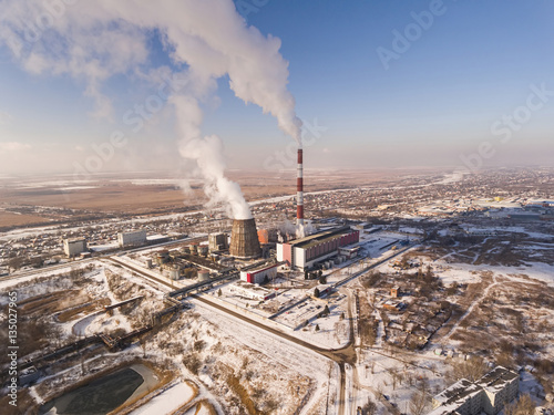 Smoking pipes of thermal power plant against blue sky in winter time. Aerial view.