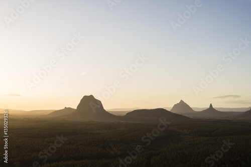 The Glasshouse mountains are silhouetted during a sunset over the Sunshine Coast, Queensland, Australia