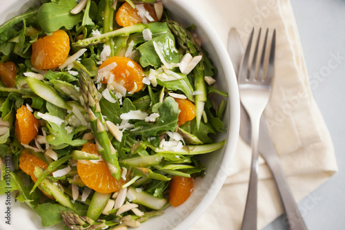 A bowl of asparagus salad with orange slices, almond slices, and orange vinaigrette