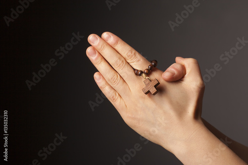Hands with cross on dark background