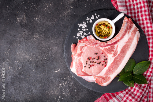 Raw meat on dark background. Raw pork steak with herbs, oil and spices. Cooking meat. Copy space. Top view