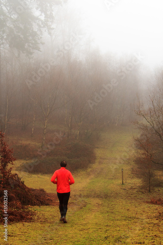 Man jogging in woodland on a foggy misty morning