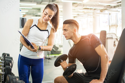 Female personal trainer showing exercise results to her male client in a gym.