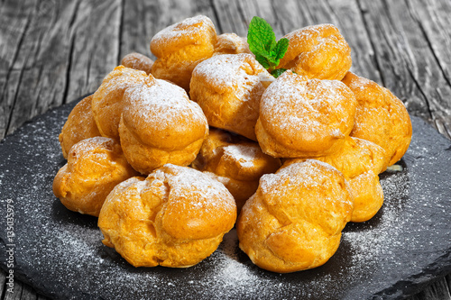 Delicious profiteroles filled with cream on slate plate photo