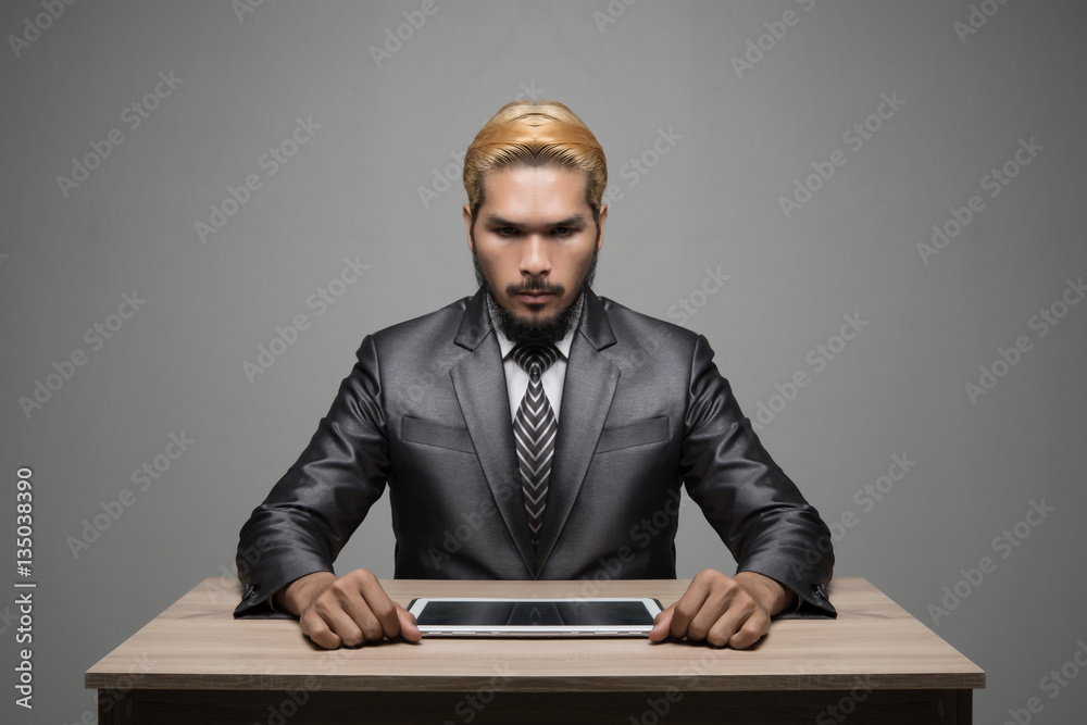 Handsome young businessman working with touchpad while sitting i Handsome young businessman working with touchpad while sitting i