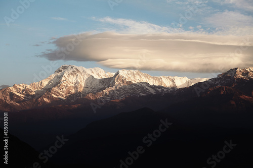 Morning in the Himalayas. Gorgeous sunny winter landscape with clear sky and snowy peaks illuminated with bright sunshine. Scenic view of clouds piling up over mountains  Highlands and altitude