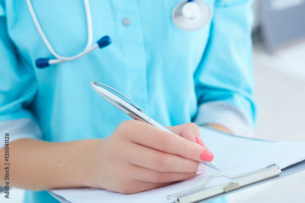 Female medicine doctor hand holding silver pen writing something on clipboard closeup. - obrazy, fototapety, plakaty 
