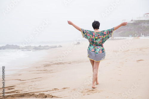 Portrait of a Happy mature woman with outspread arms Enjoying freedom on the Ocean Beach. Freedom of Travel Vacation. Wellness and Happiness Lifestyle Concept. Portugal. Santa Cruz