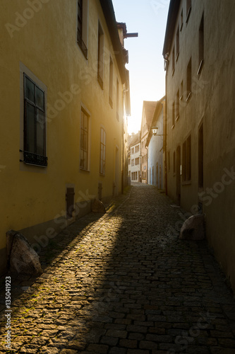 Empty narrow cobblestone street lit by morning sun. Old street in ancient town of Rothenburg ob der Tauber in Germany  Europe.