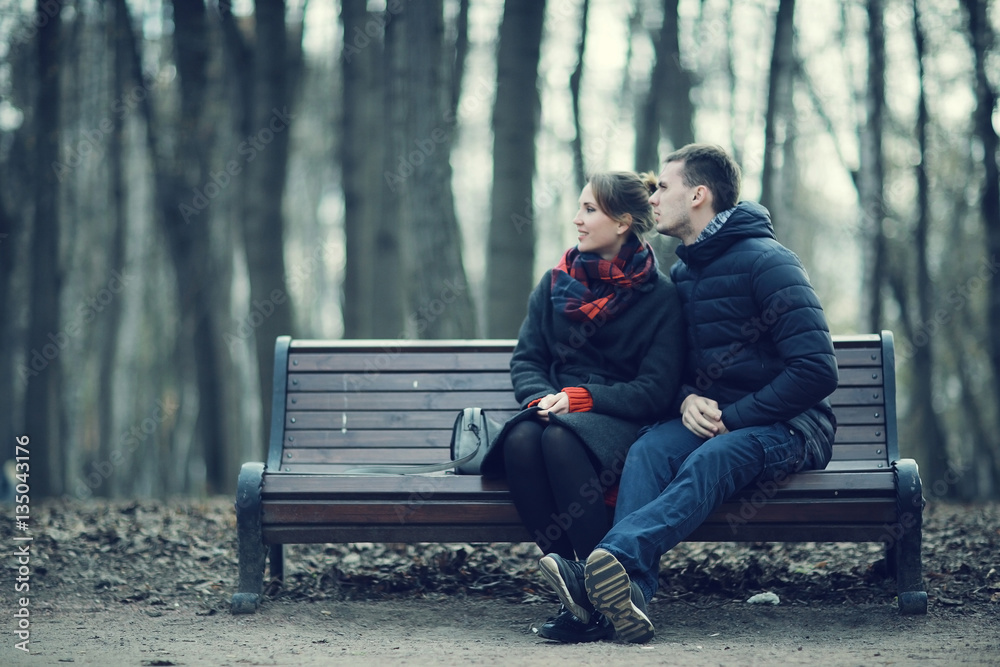 couple cuddling on a bench in winter couple cuddling on a bench in winter