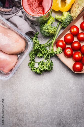Healthy food with raw chicken breast, fresh seasoning and vegetables on gray stone background